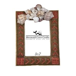 A woven wooden frame with red accents, topped with an assortment of seashells.